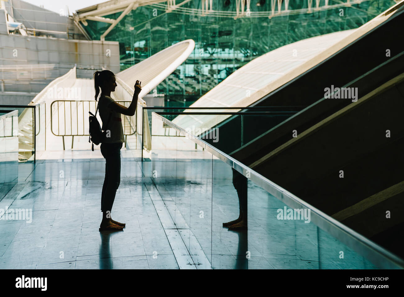 Silhouette contre la lumière de la jeune femme à prendre des photos dans un immeuble moderne Banque D'Images