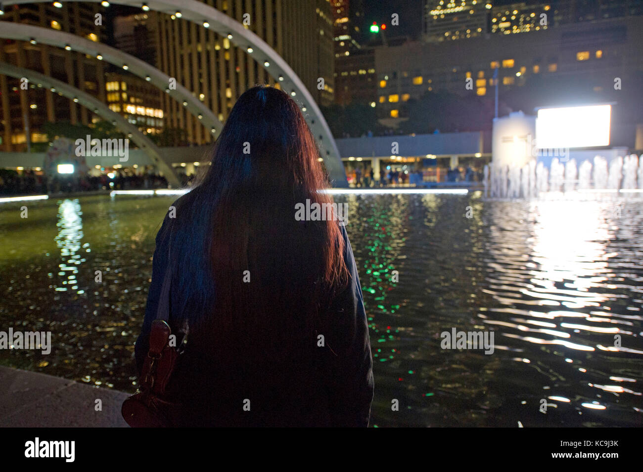 Femme debout à l'étang sur Nathan Philips Square à Toronto Banque D'Images