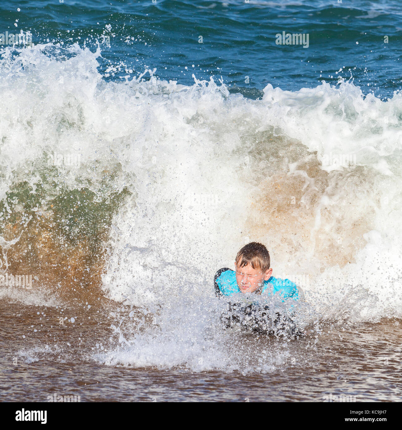 Avon, Outer Banks, Caroline du Nord, USA. Pre-adolescent dans l'Atlantique Surf sur sa planche de surf. Banque D'Images