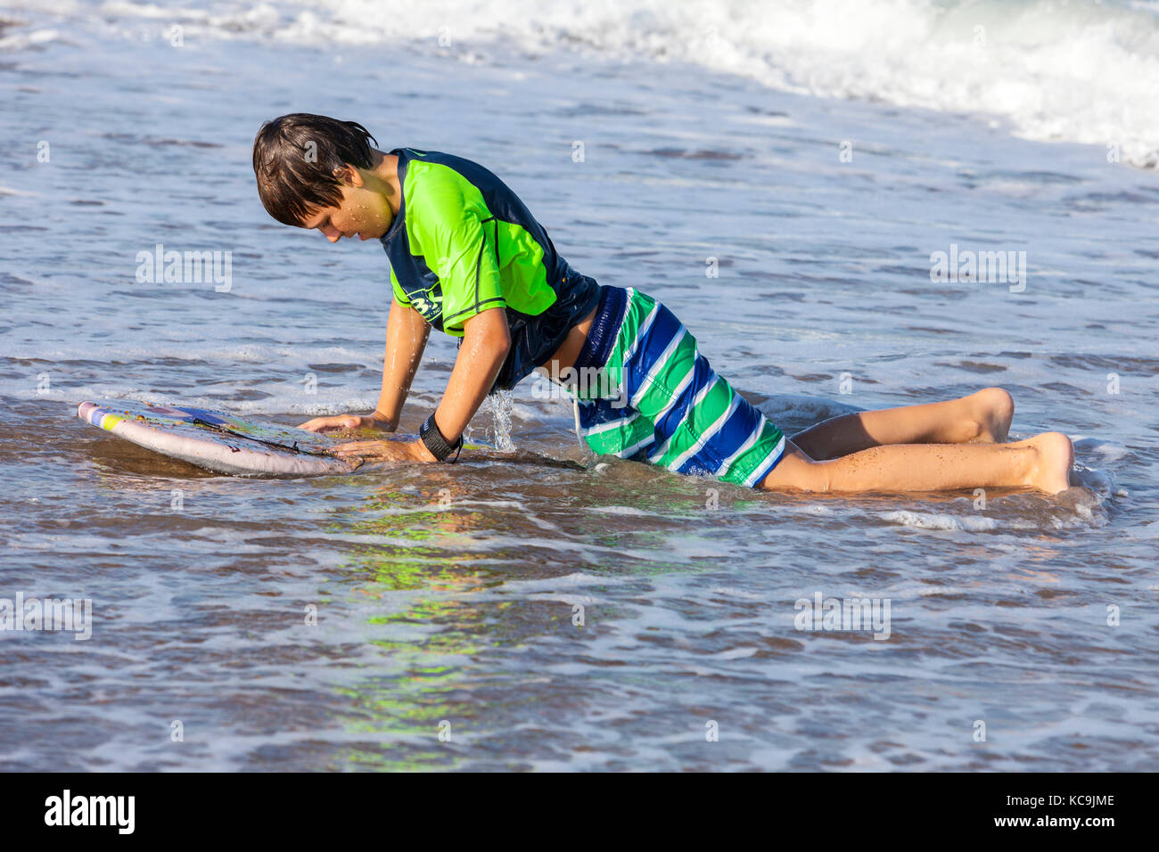 Avon, Outer Banks, Caroline du Nord, USA. Pré-adolescent est échoué sur la plage avec Boogie Board. Banque D'Images