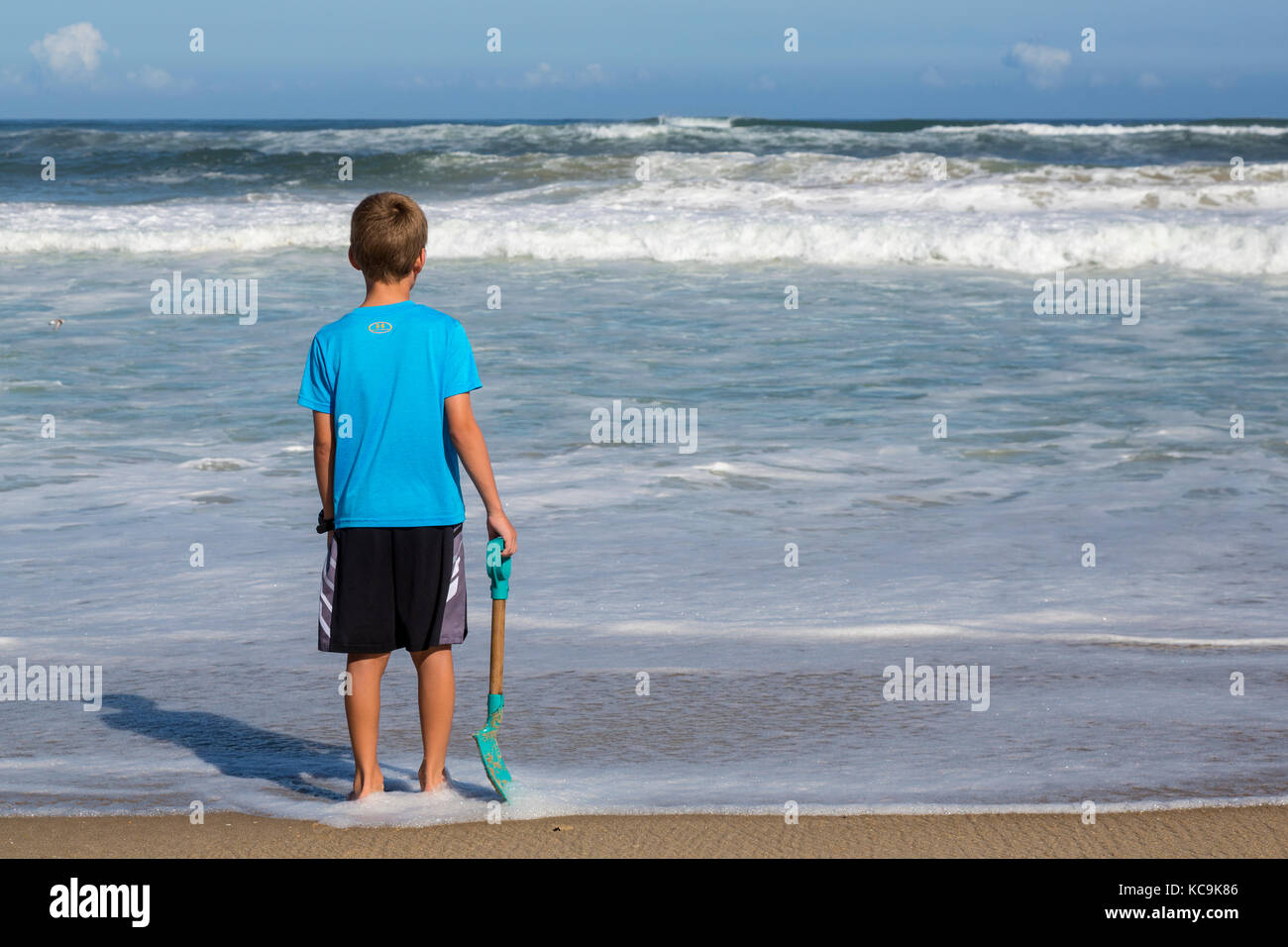 Avon, Outer Banks, Caroline du Nord, USA. Jeune garçon en contemplant les vagues de l'Atlantique. Banque D'Images