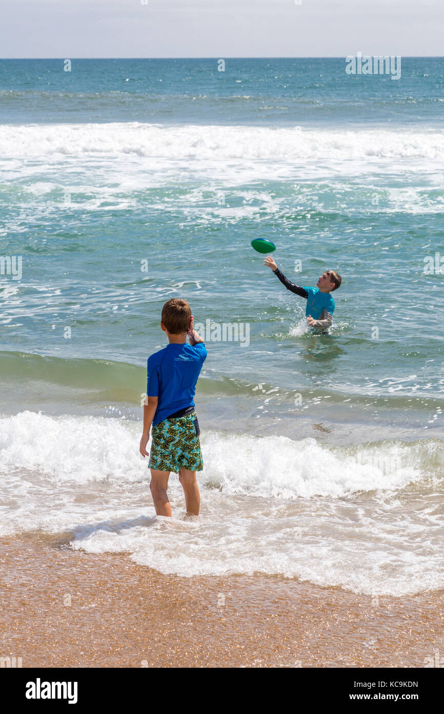 Avon, Outer Banks, Caroline du Nord, USA. Les jeunes garçons américains dans les vagues, s'agite le football. Banque D'Images