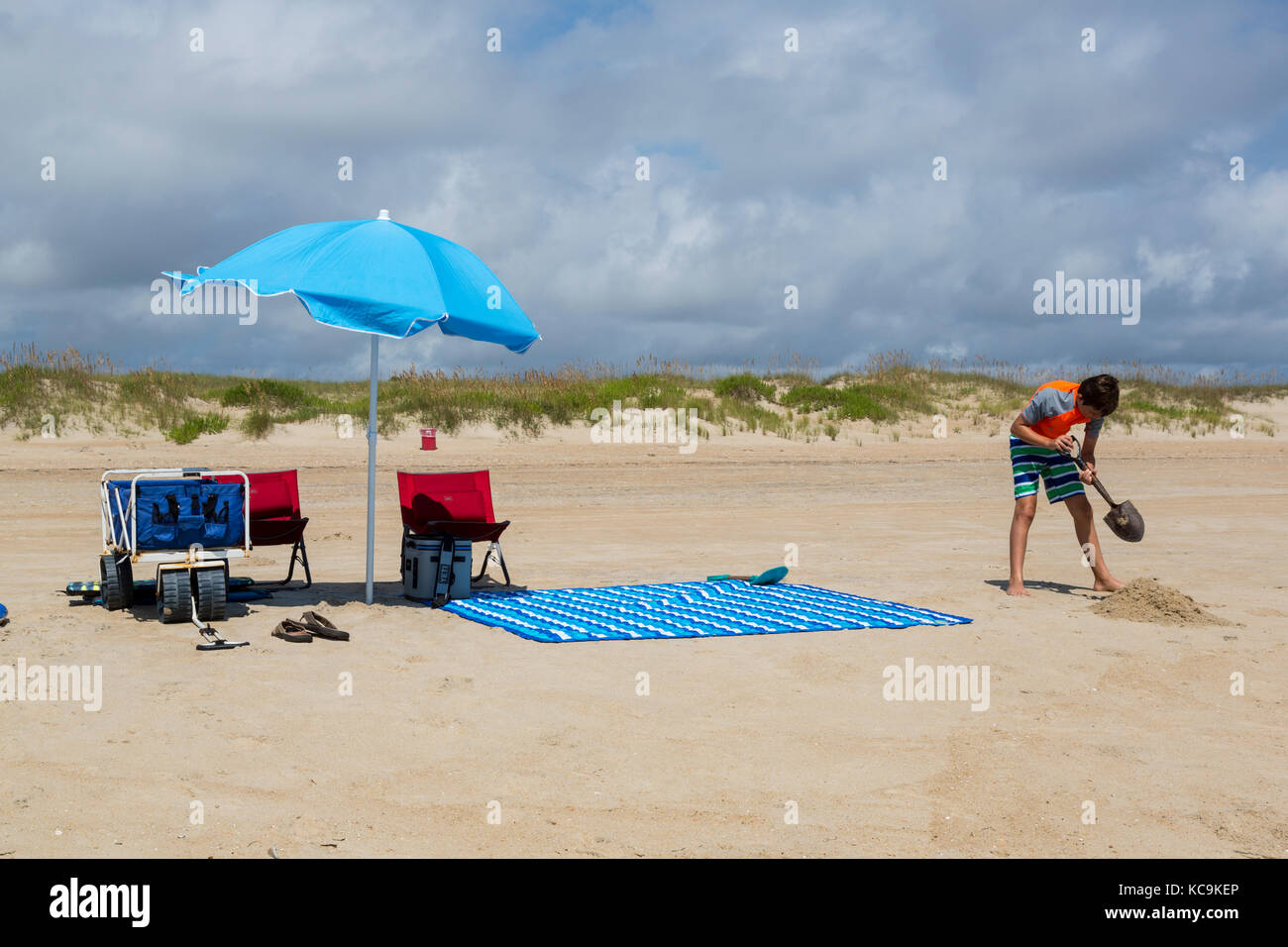 Avon, Outer Banks, Caroline du Nord, USA. Jeune garçon de creuser sur la plage. Banque D'Images