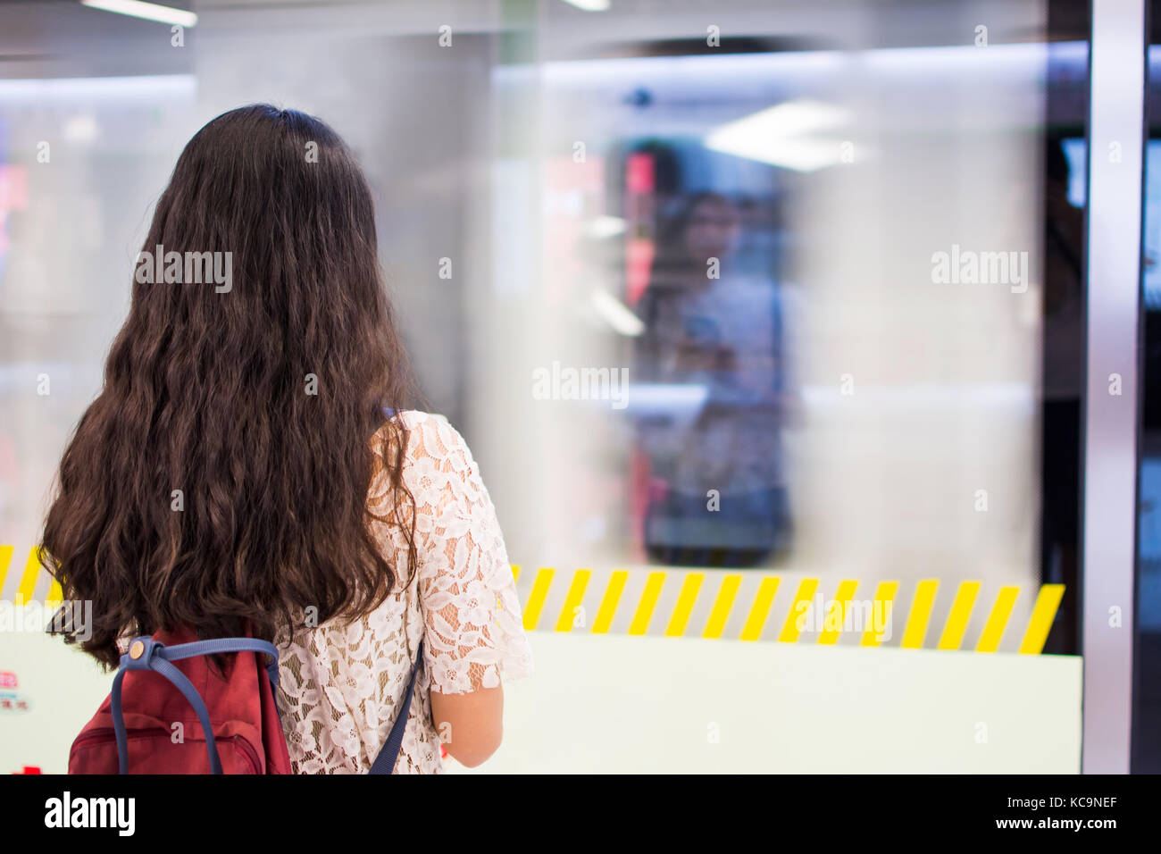 Jeune fille en attente de train arrivant à la station de métro Banque D'Images