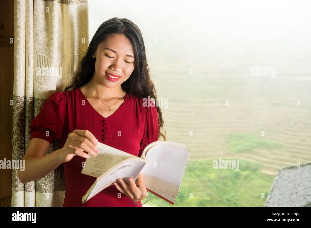 Jeune fille lisant un livre par la fenêtre avec vue sur terrasse de riz Banque D'Images