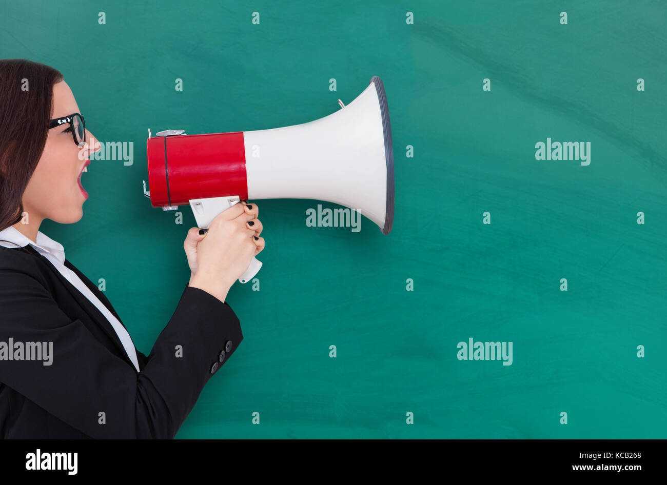 Young businesswoman crier par mégaphone contre tableau noir Banque D'Images