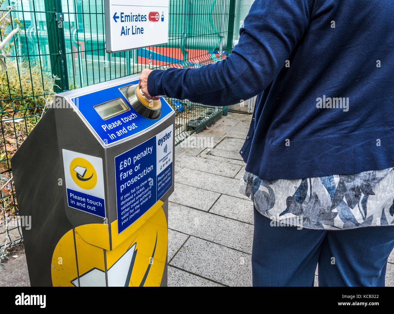 Une femme sur sa carte bancaire de banlieue sur une machine de paiement sans contact pour le Docklands Light Railway (DLR) à l'Est de Londres, Angleterre, Royaume-Uni. Banque D'Images