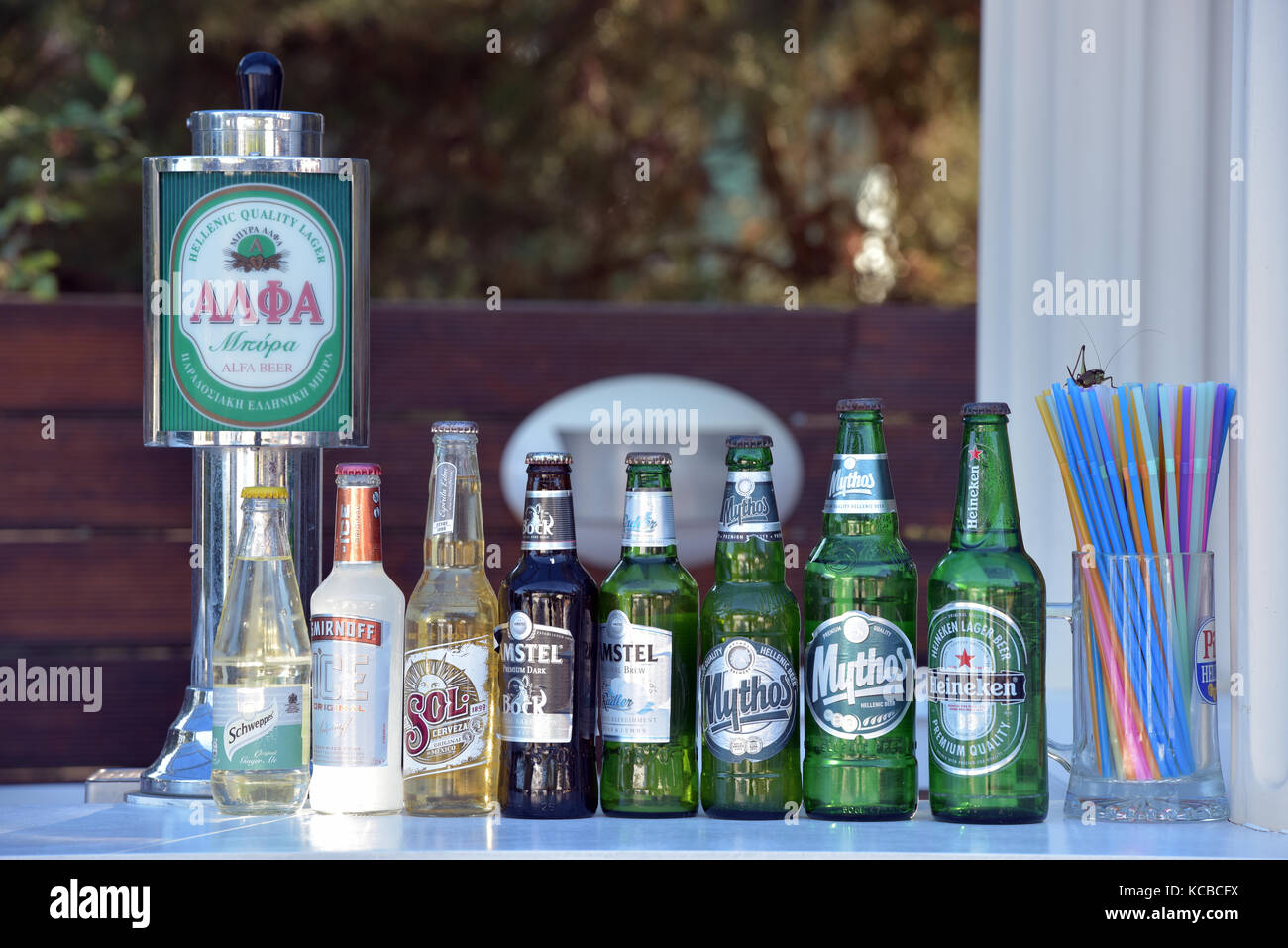 Bouteilles de bière blonde et de la bière à côté d'une bière pression ou pompe à la bar de l'hôtel avec des pailles en plastique et des boissons figurant sur l'écran donnant un choix de boissons. Banque D'Images