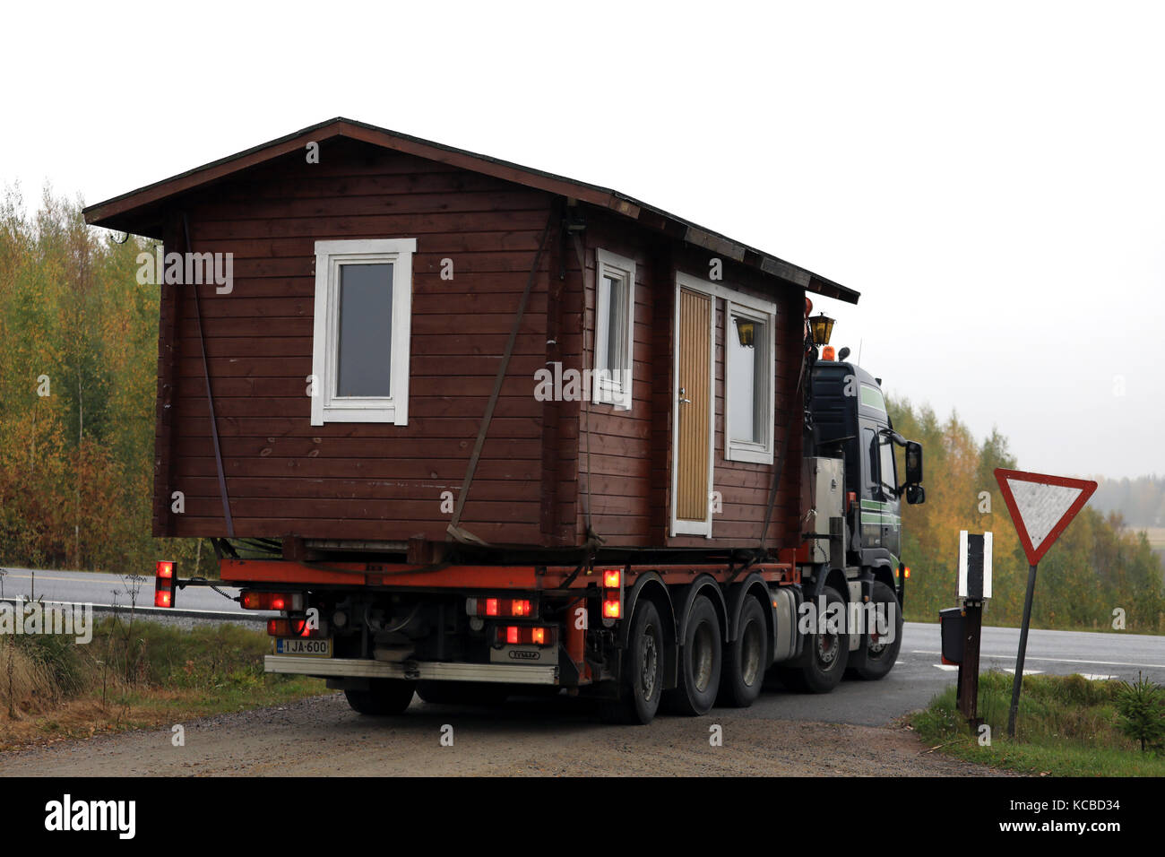 Salo, Finlande - le 30 septembre 2017 : chalet en bois par Volvo fm transport de semi tauno salminen ky s'arrête au signe de rendement avant d'entrer sur la route principale sur une fo Banque D'Images