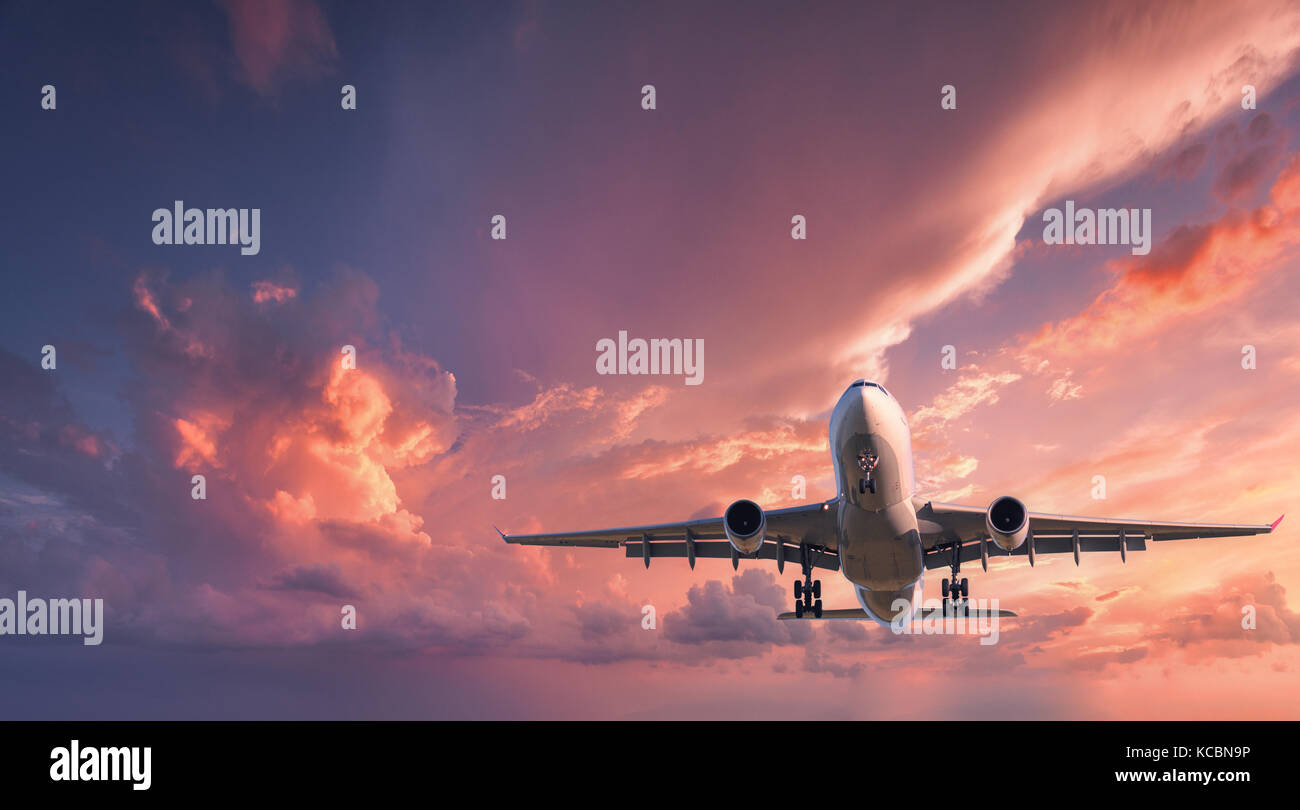 Avion à l'atterrissage. Paysage avec passager blanc est un avion volant dans le ciel avec nuages colorés rouge au coucher du soleil. billet d'arrière-plan. passager airlin Banque D'Images