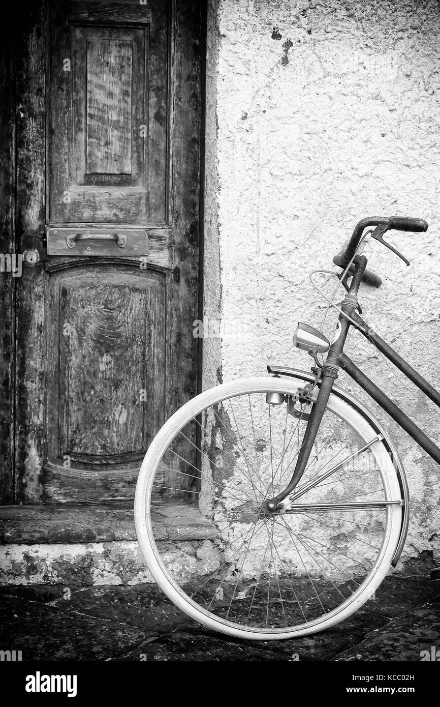 Vieilles portes et mur avec vélo d'époque, photo noir et blanc. Banque D'Images