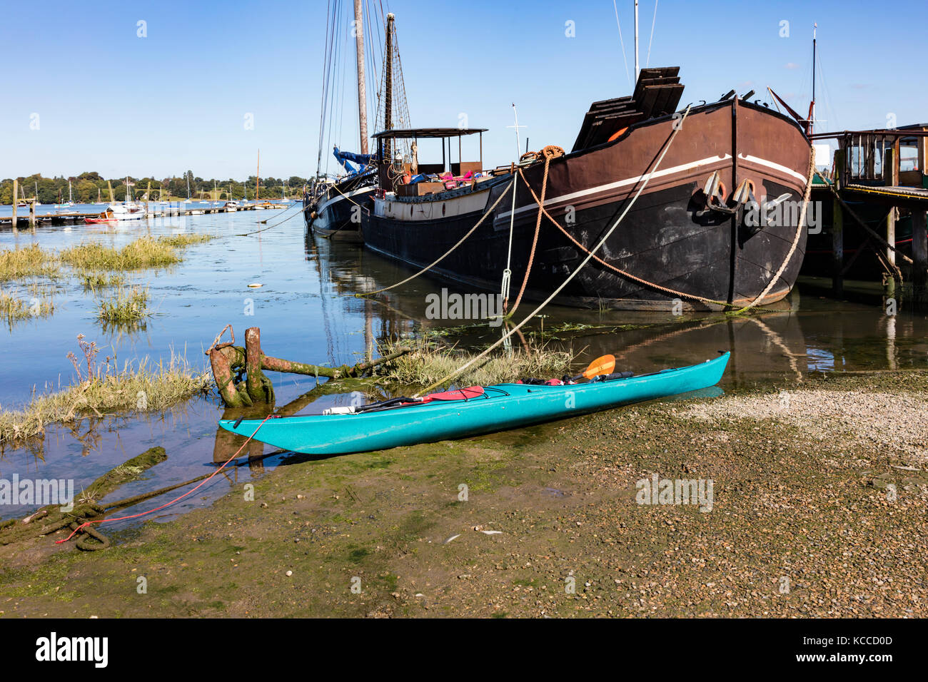 Un canot turquoise attaché sur la boue à la broche Mill à côté de péniches amarrées, courbes des coques et les amarres, Chelmondiston, Essex, UK Banque D'Images