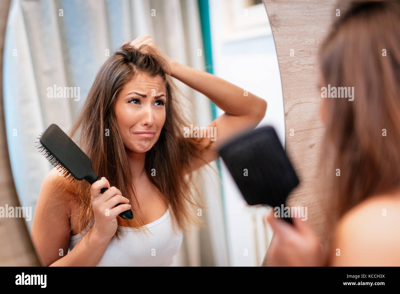 Portrait d'une jeune femme a souligné service avec les cheveux ébouriffés et déplut à sur son miroir de salle de bains. focus sélectif. Banque D'Images