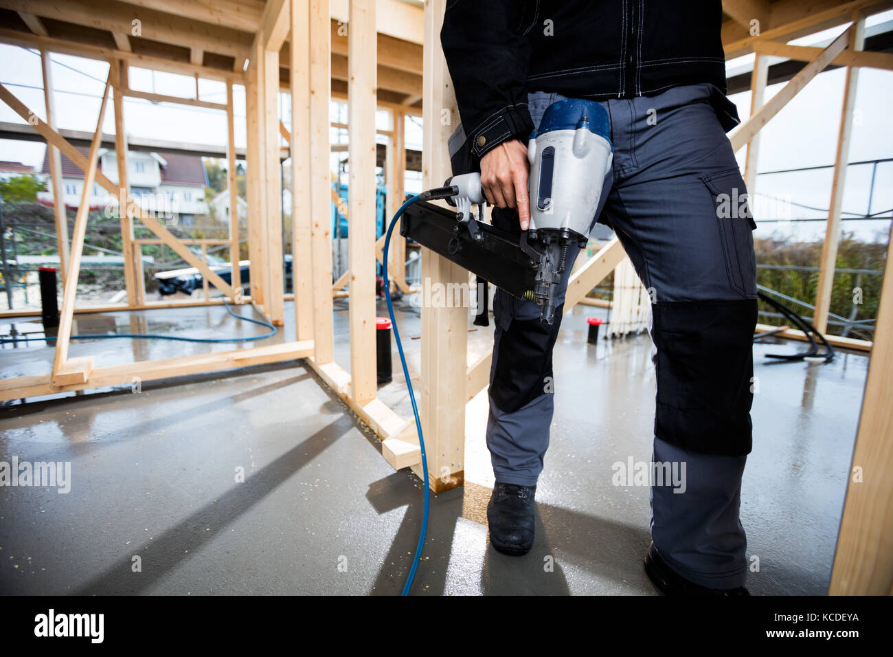 La section basse de male carpenter holding drill at construction site Banque D'Images