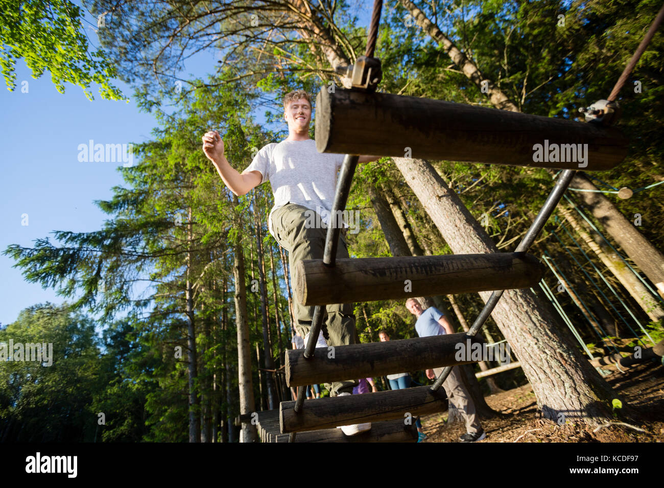 Low angle view of young businessman crossing log bridge in forest Banque D'Images