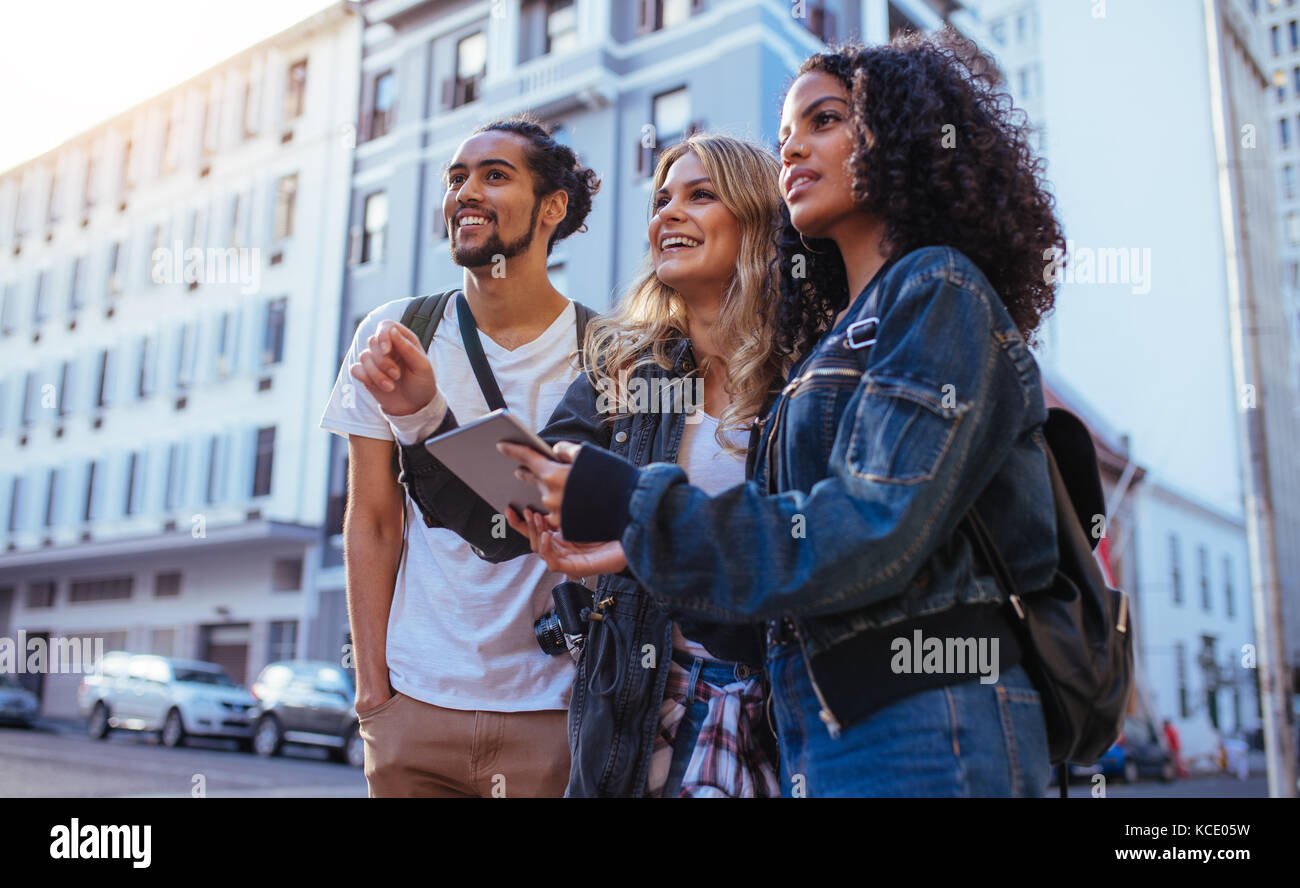 Les touristes à l'aide d'outils de navigation pour explorer la ville. L'homme avec deux femmes à la découverte de la ville d'amis des accessoires de voyage. Banque D'Images