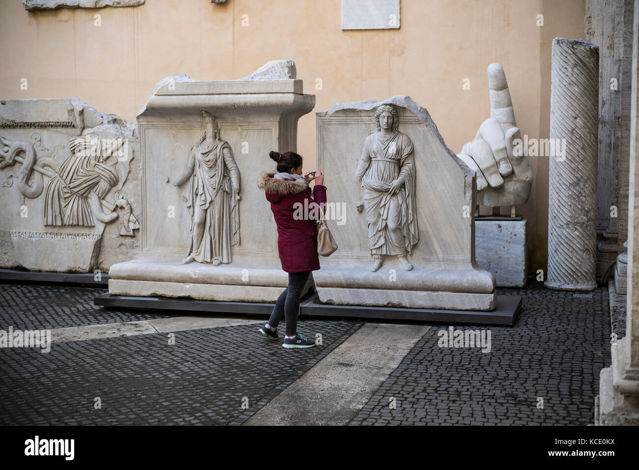 Rome. L'Italie. Visiteur à la recherche à reliefs du Temple d'Hadrien dans la cour du Palais des Conservateurs, Musées du Capitole. Banque D'Images