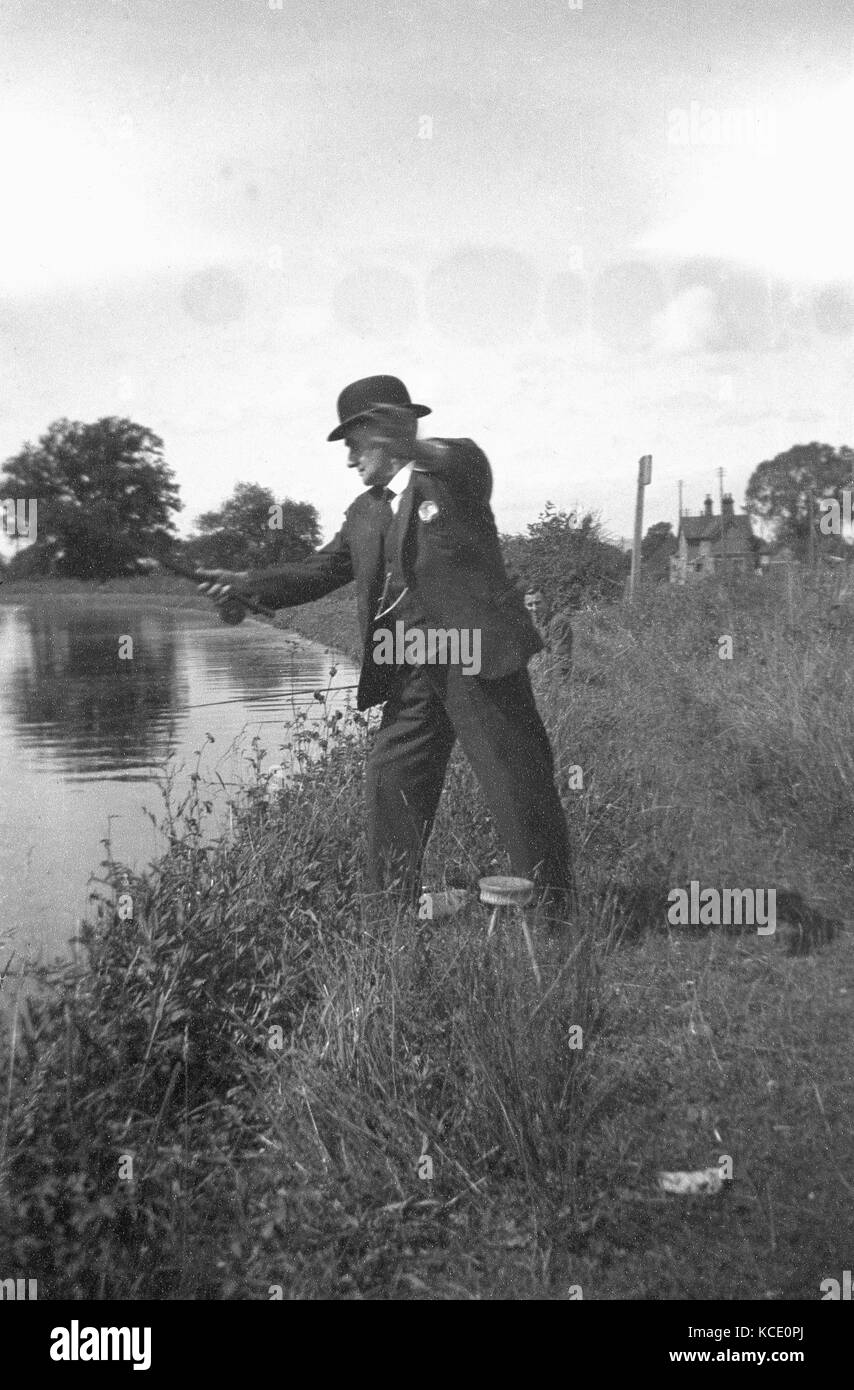 Années 1930, photo historique montrant un homme âgé à la pêche dans une rivière portant un costume trois pièces et chapeau melon, Angleterre, Royaume-Uni. Banque D'Images