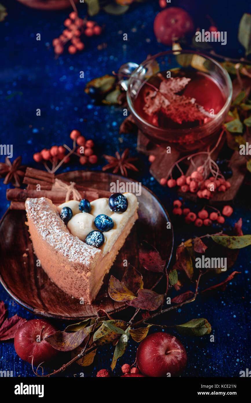 Close-up d'un morceau de tarte à la citrouille avec du sucre en poudre dans une scène d'automne sombre de fumée. sweet halloween concept, copie espace conceptuel toujours stylisés. vie avec les feuilles d'automne et de baies. Banque D'Images