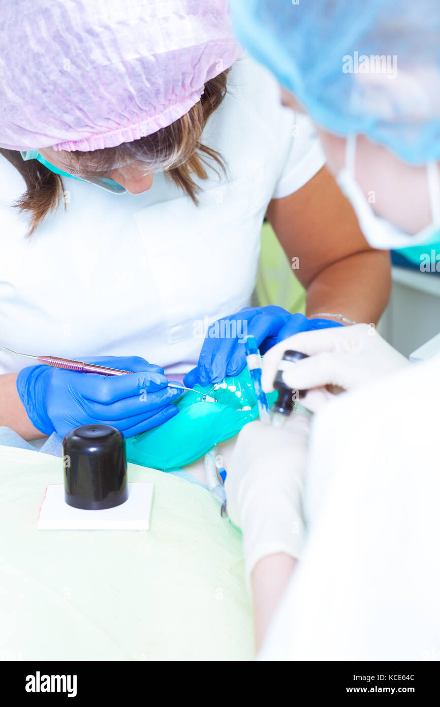 Deux dentistes Femmes en blanc uniforme médical et son adjointe, faire une procédure pour le traitement des dents de la carie et nettoie les dents de plaque en Banque D'Images