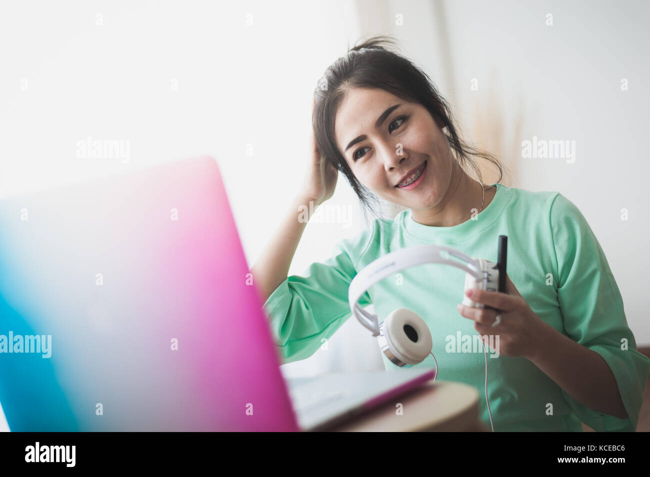 Jeune femme asiatique attrayant en tenant le casque tout en travaillant avec un ordinateur portable. internet des objets pour le mode de vie moderne et freelance travailleur con Banque D'Images