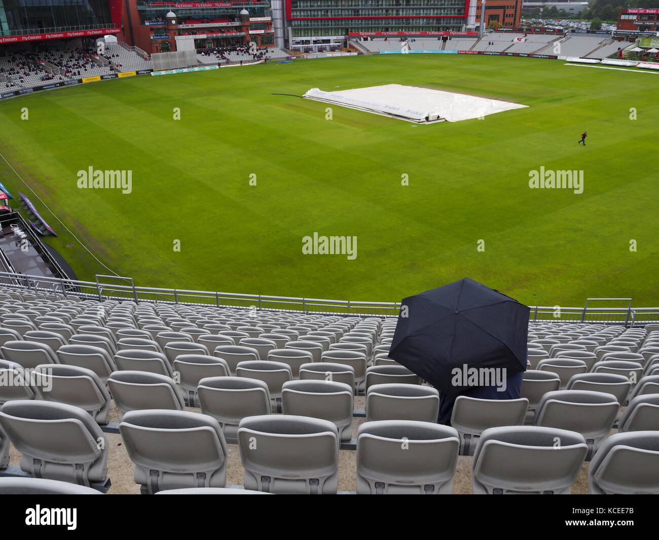 Personne assise sous la pluie lors d'un match de cricket Banque D'Images