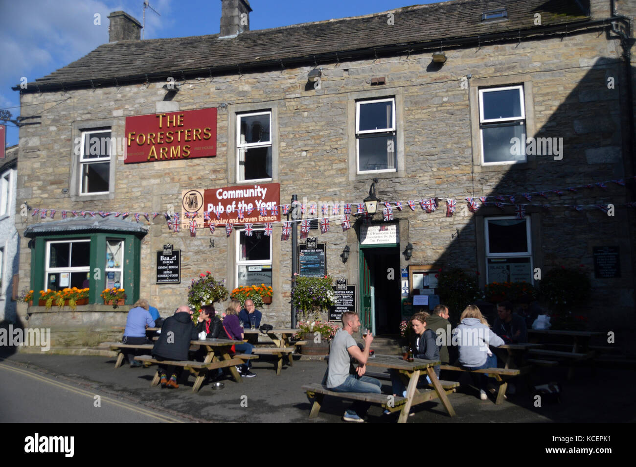 Personnes buvant dans le soleil du soir aux Foresters Arms dans le village de Grassington à Wharfedale, parc national de Yorkshire Dales, Angleterre, Royaume-Uni. Banque D'Images