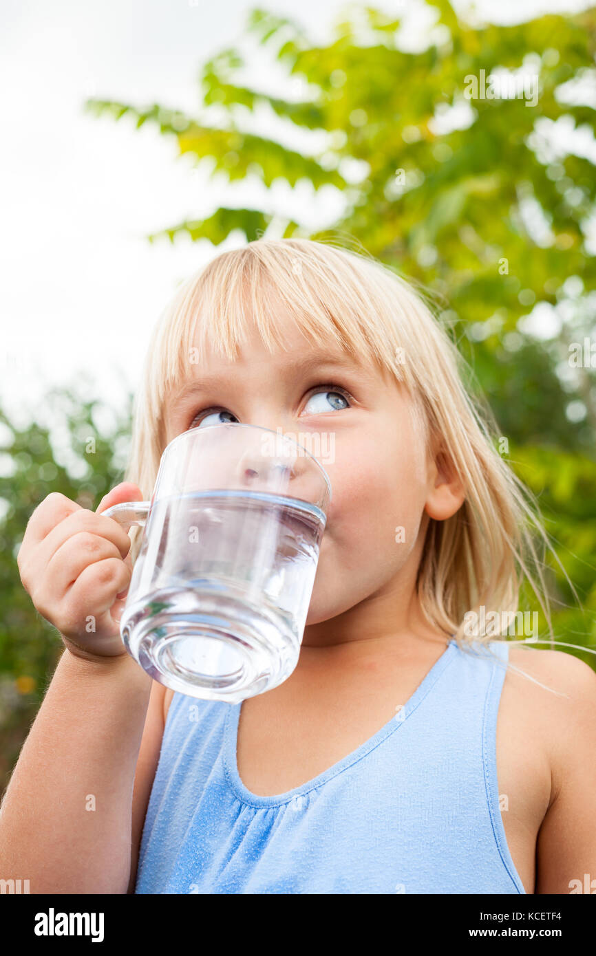 Petite fille de l'eau potable à la côte dans un jardin d'été Banque D'Images