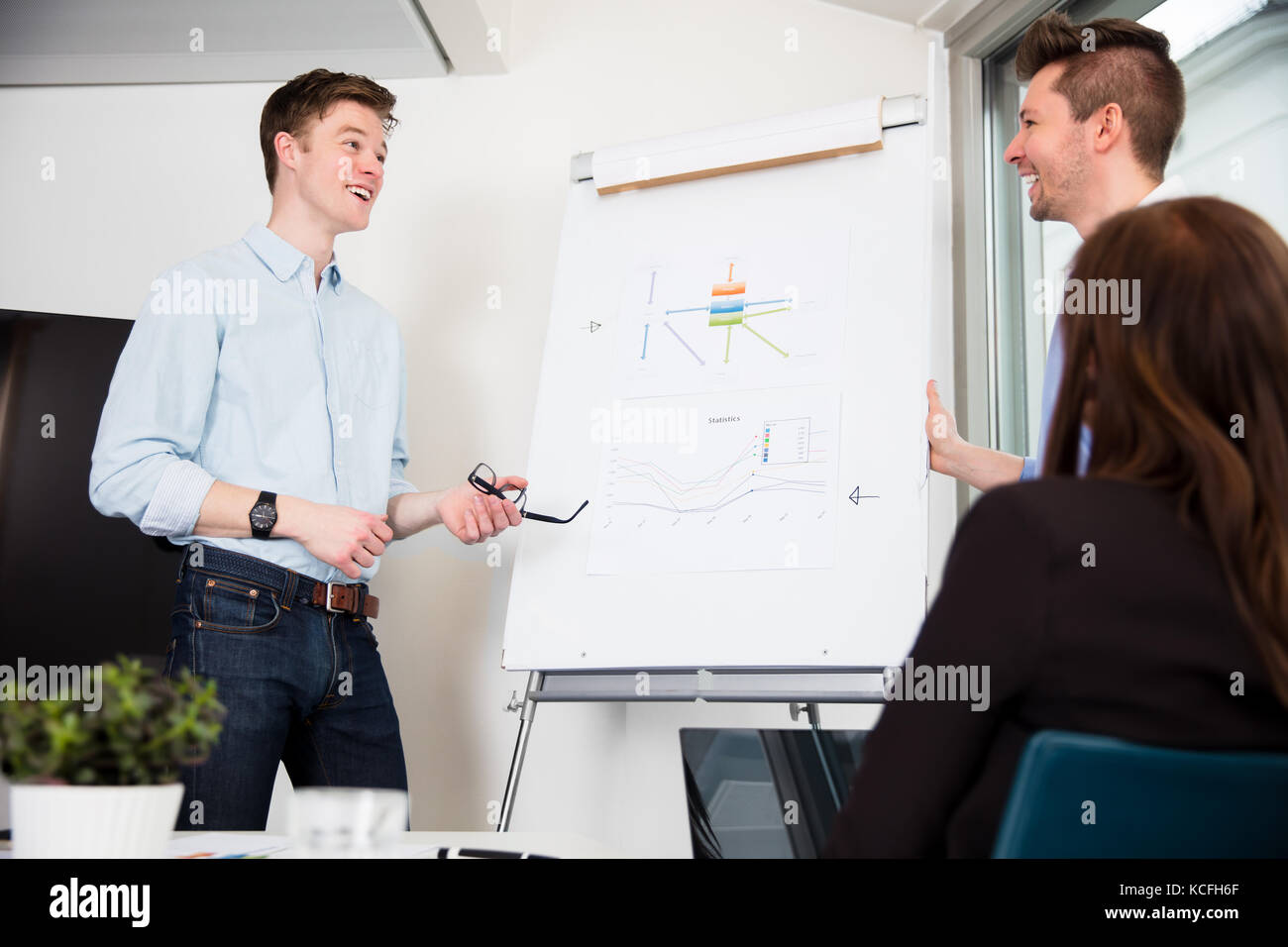 Businessmen standing par tableau de présentation in office Banque D'Images