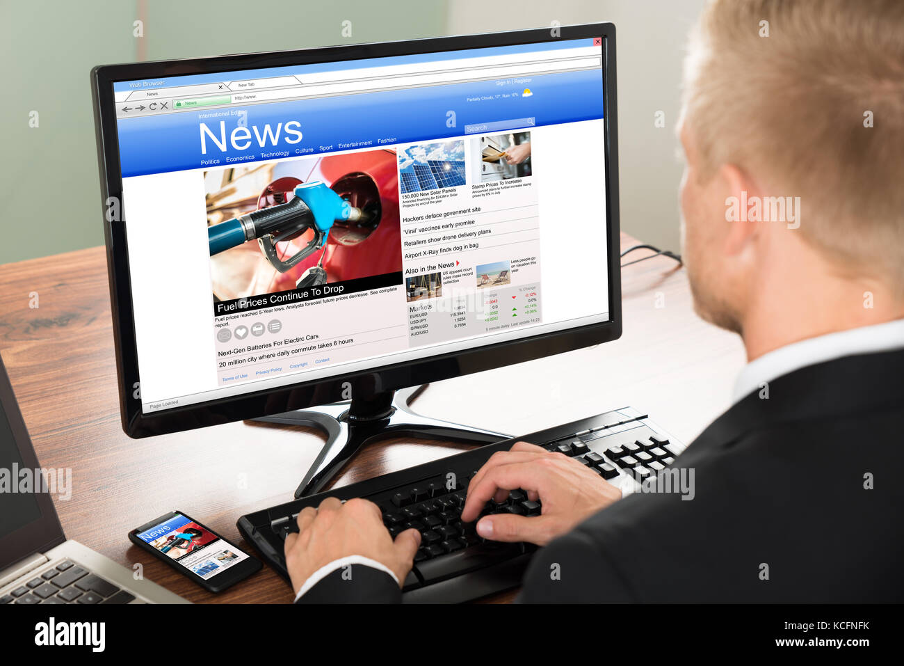 Close-up of a businessman reading news on computer at office Banque D'Images