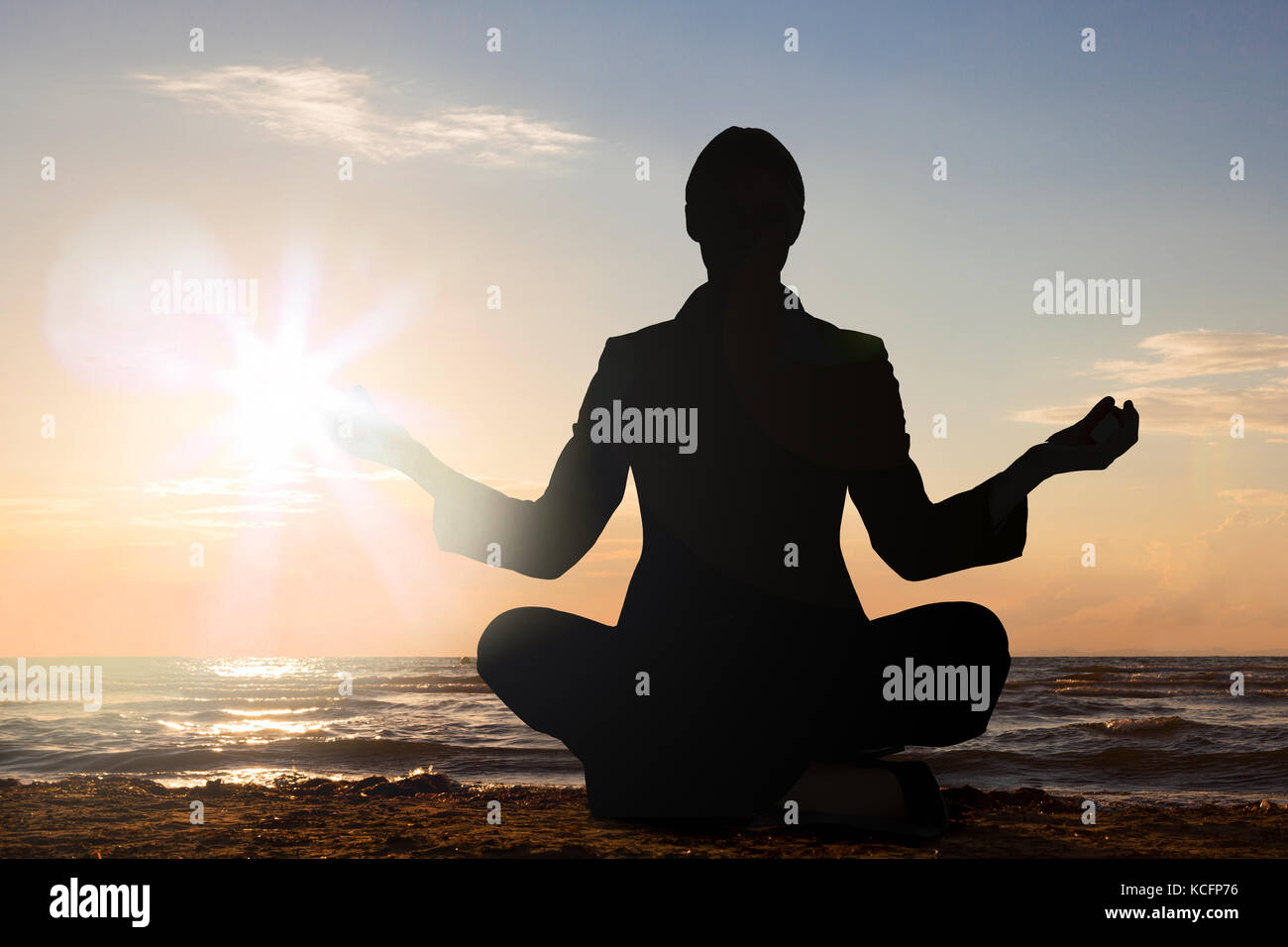 Silhouette d'une personne pratiquant le yoga sur la plage au coucher du soleil Banque D'Images