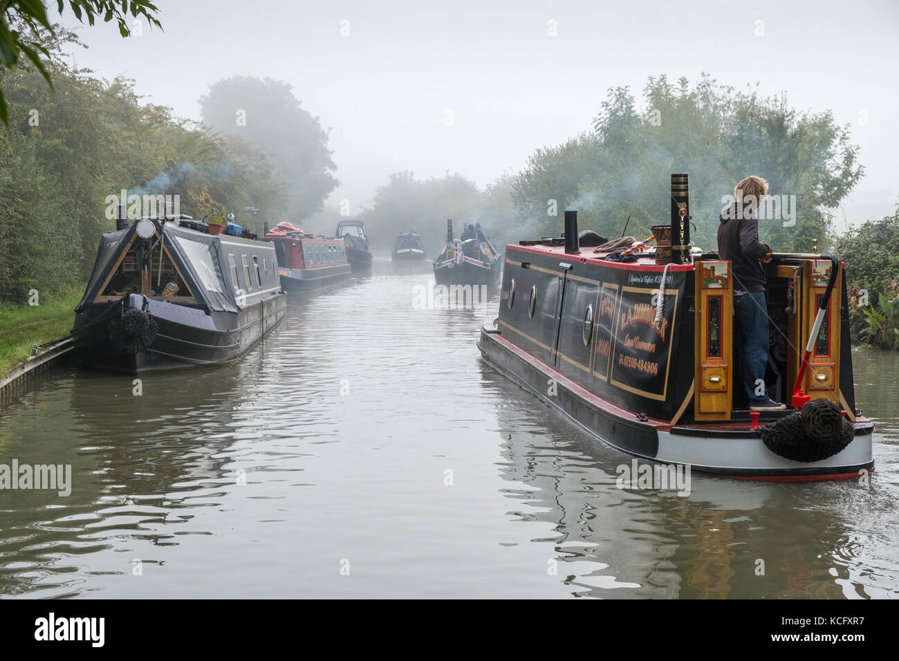 L'équipe d'un groupe de trois narrowboats traditionnelles imputées sur d'autres embarcations amarrées passé sur l'Ashby de la Zouche canal, près de Stoke Golding. Banque D'Images