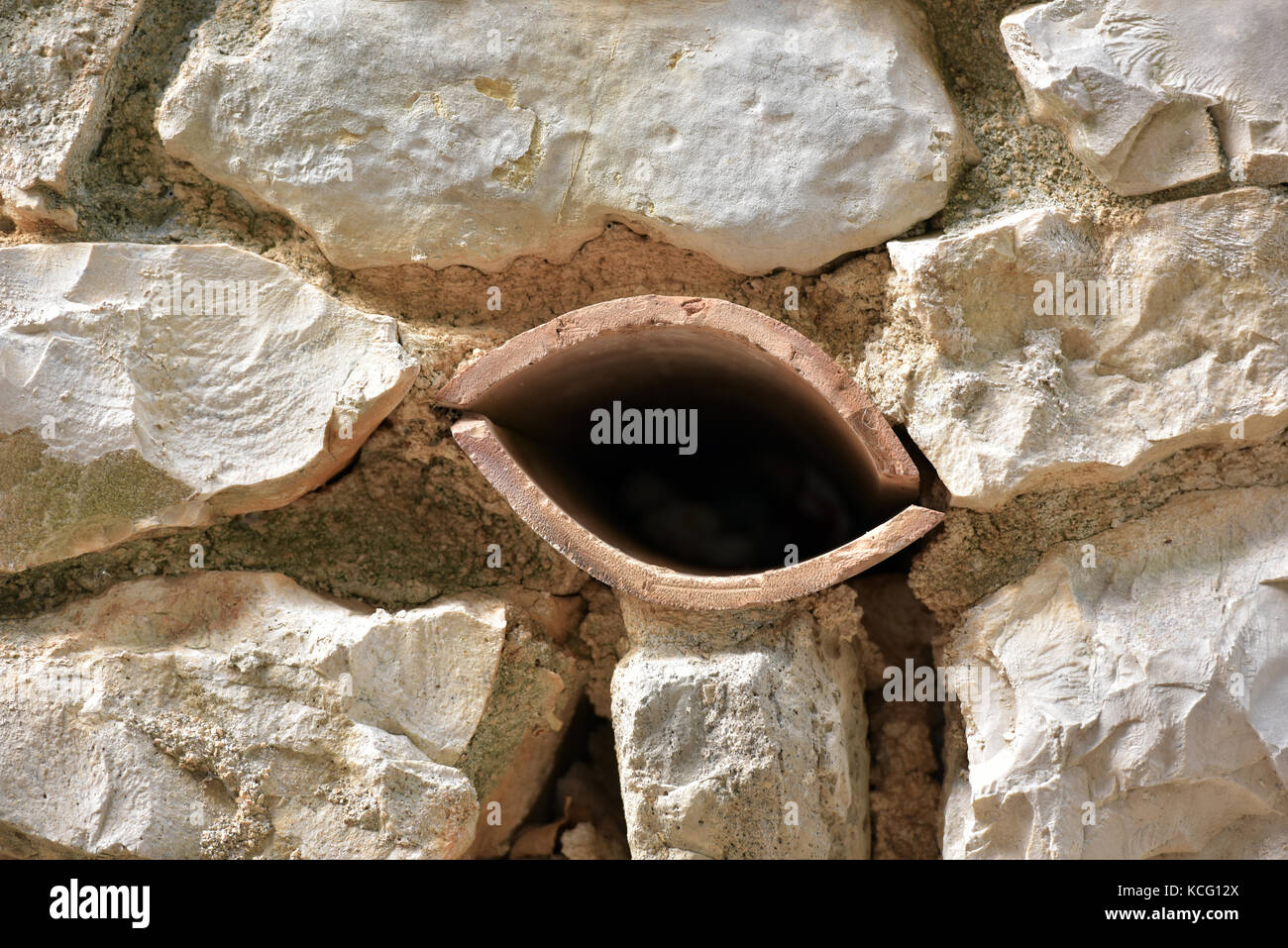 Un tuyau de drainage dans un mur de pierre à la forme d'une paire de lèvres ou une bouche.Les matériaux de construction, d'humour et drôles de formes. Banque D'Images