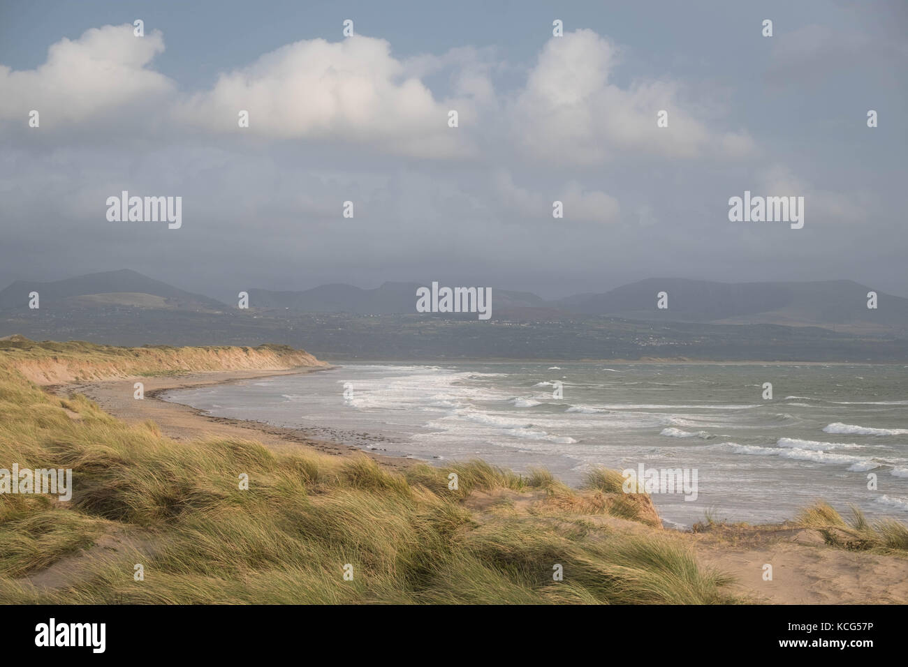 Dunes de sable, la plage et vagues avec les montagnes de Snowdonia dans la distance à la plage de newborough, Isle of Anglesey, au nord du Pays de Galles, Royaume-Uni. Banque D'Images