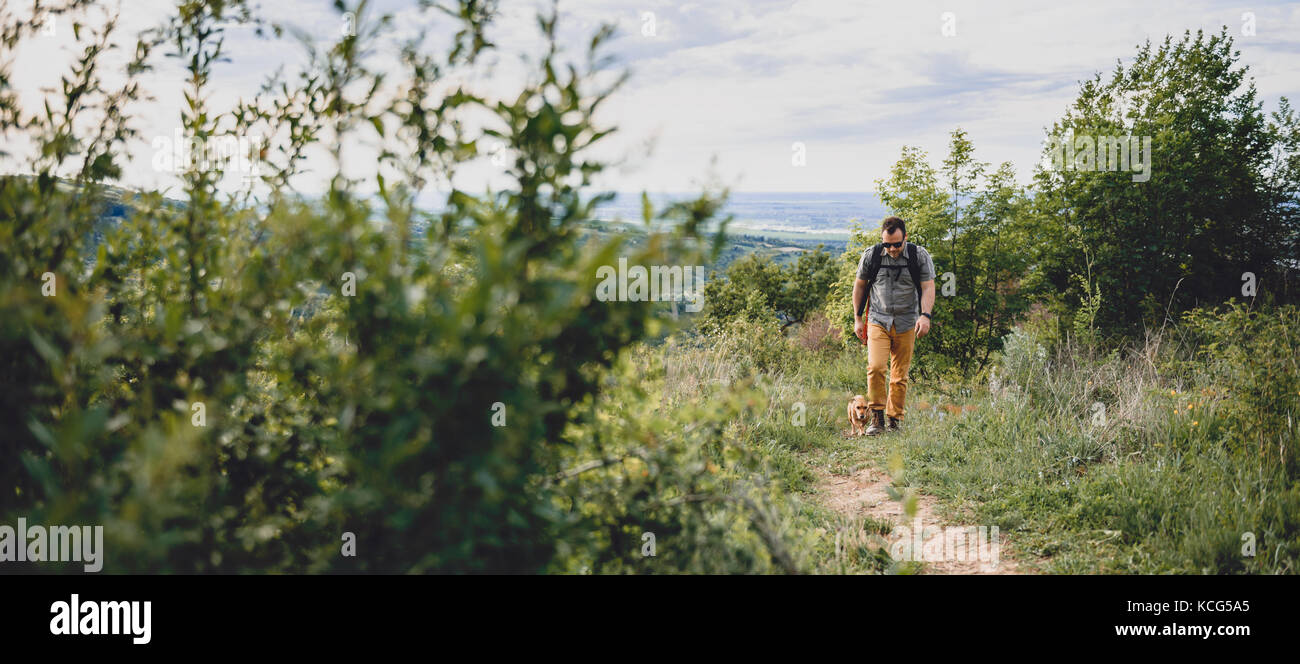 Homme avec un chien à marcher le long d'un sentier de randonnée sur la montagne Banque D'Images