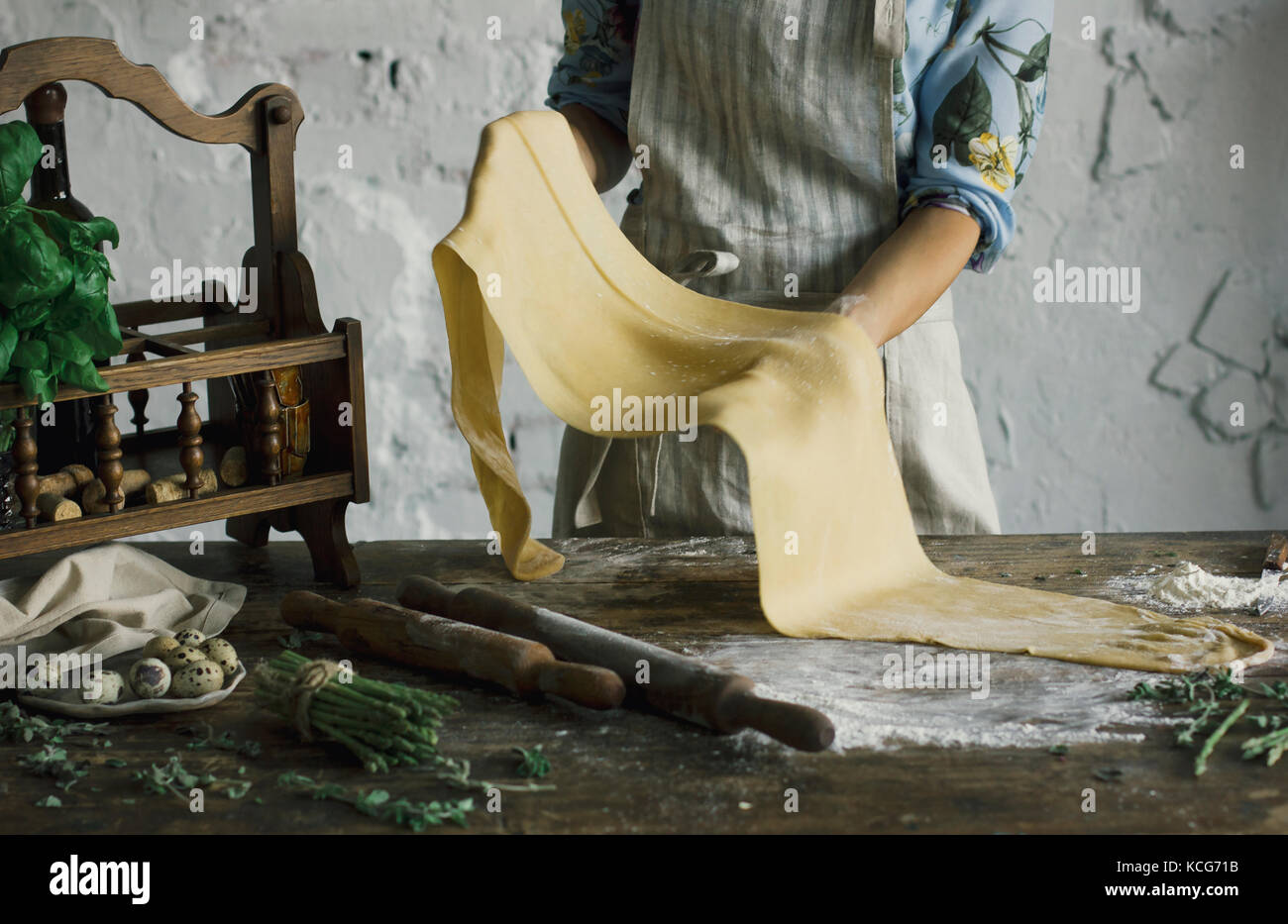 Jeune femme tenant un tablier dans la pâte pour des pâtes à la cuisine rustique Banque D'Images