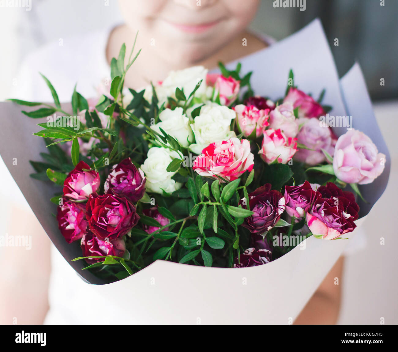 L'enfant smiling, roses blanches et roses dans le papier à motifs floraux Banque D'Images