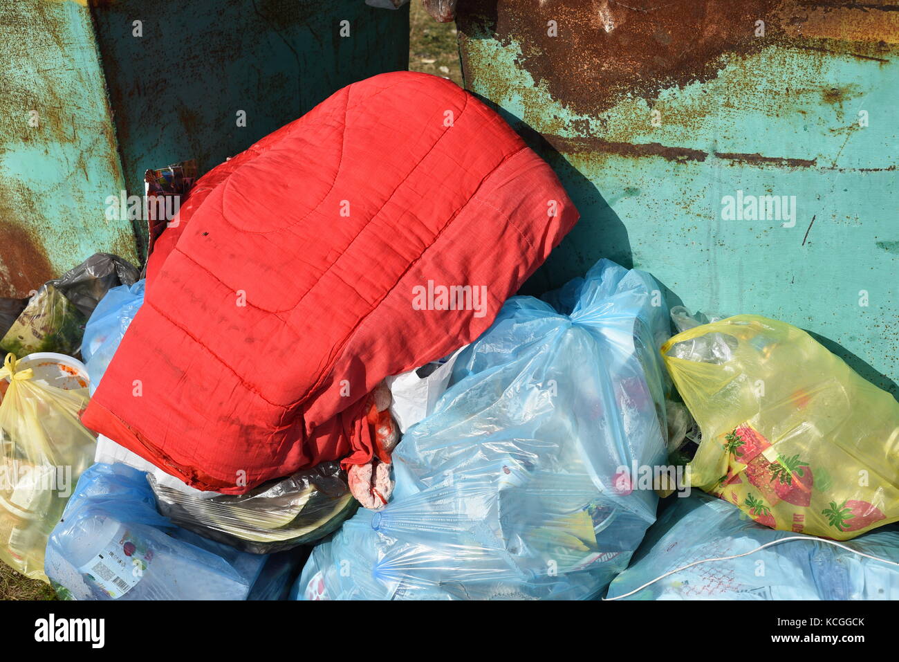 Les sacs de déchets jetés portant sur le côté d'un bac de recyclage de métal vert Banque D'Images