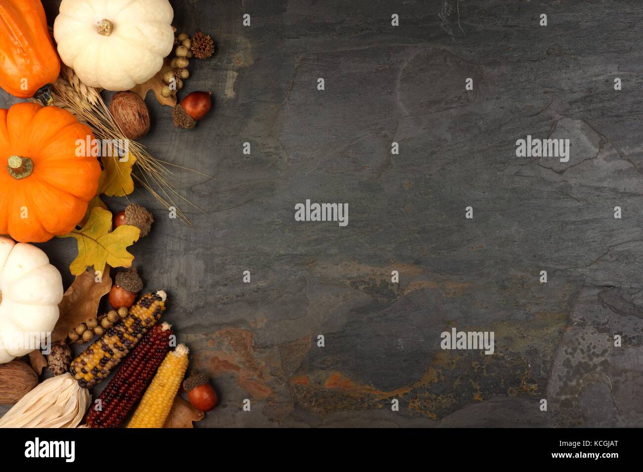 Côté frontière avec la récolte d'automne citrouilles, les feuilles et les noix sur une ardoise background Banque D'Images