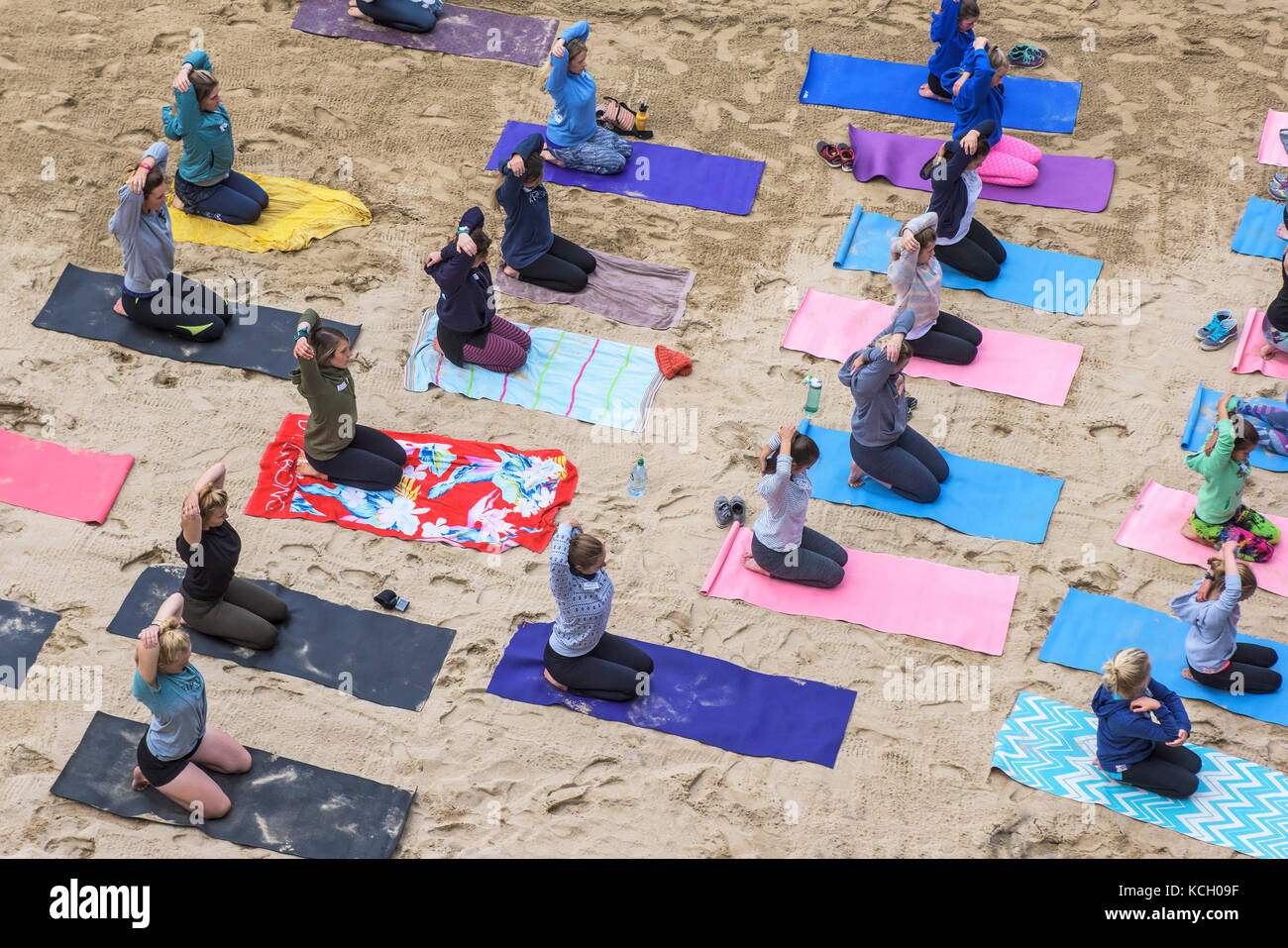 Yoga sur une plage - les femmes pratiquant le yoga sur une plage à Newquay, Cornwall Banque D'Images