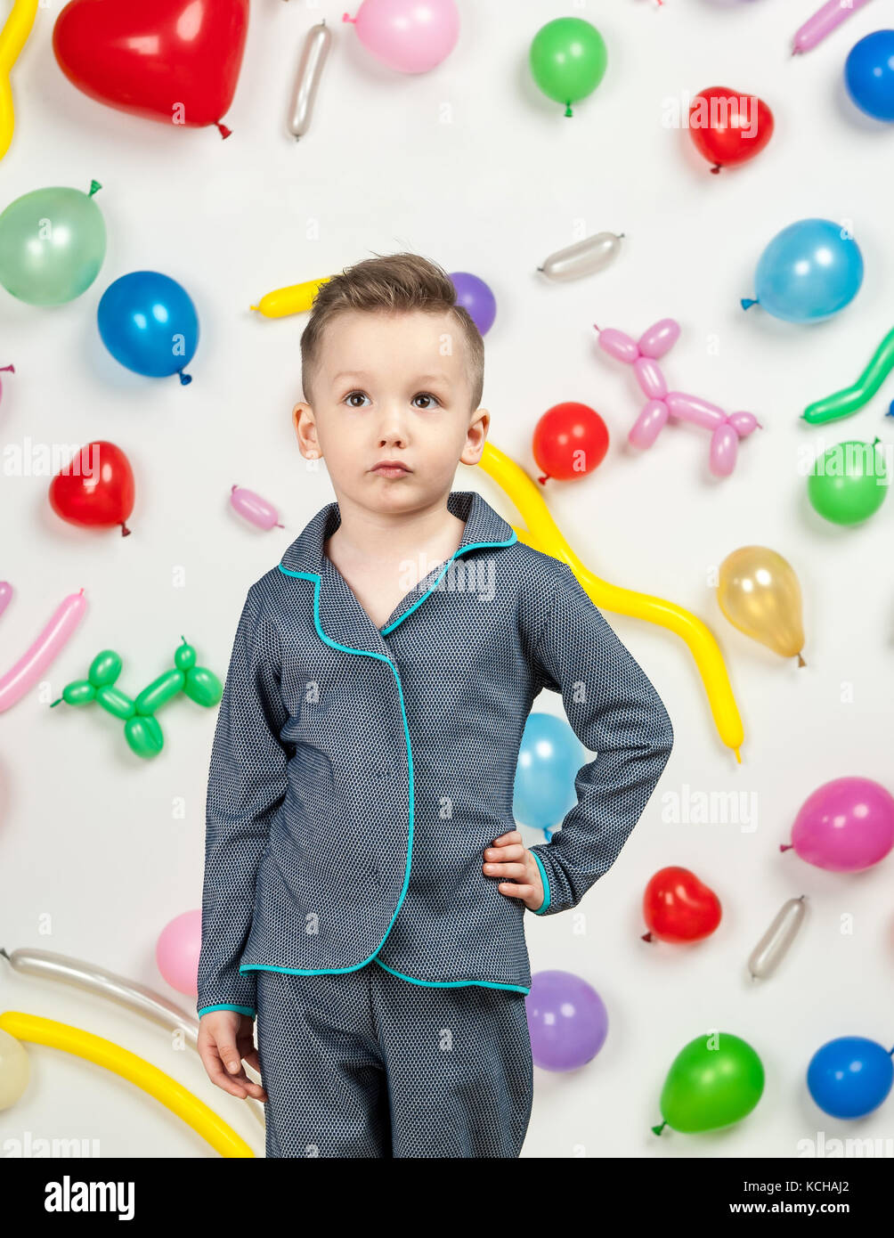 Garçon sur un fond blanc avec des ballons colorés. garçon en pyjama sur un fond blanc avec des ballons en forme de coeur Banque D'Images