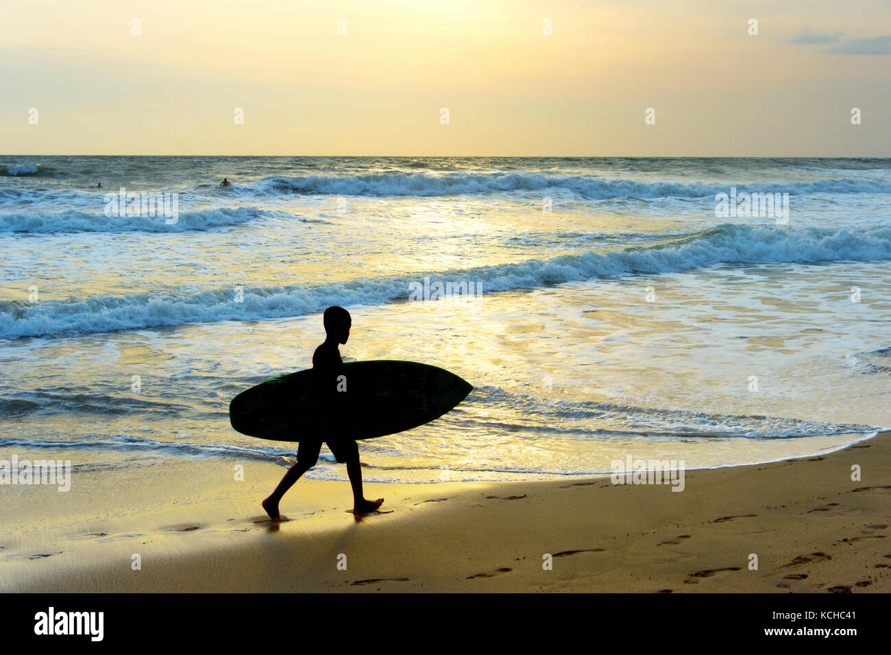 Silhouette d'un garçon de la surfer marche sur la plage. L'île de Bali, Indonésie Banque D'Images
