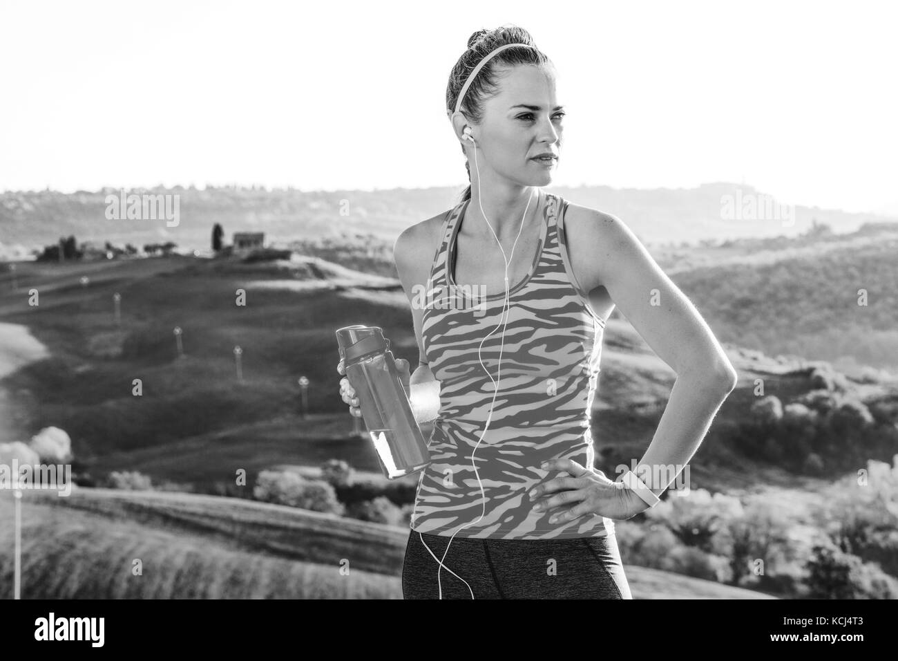 Remise en forme et une vue magique de la toscane. femme en bonne santé en bonne santé dans les équipements sportifs dans l'avant de paysages de la toscane avec une bouteille d'eau à côté Banque D'Images
