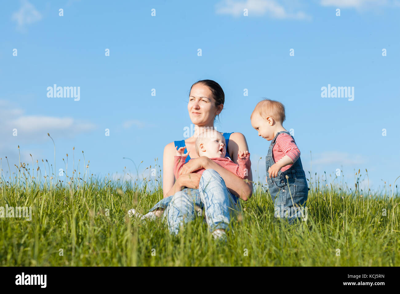 Portrait d'une mère de deux enfants. ils jouent dans l'herbe verte Banque D'Images