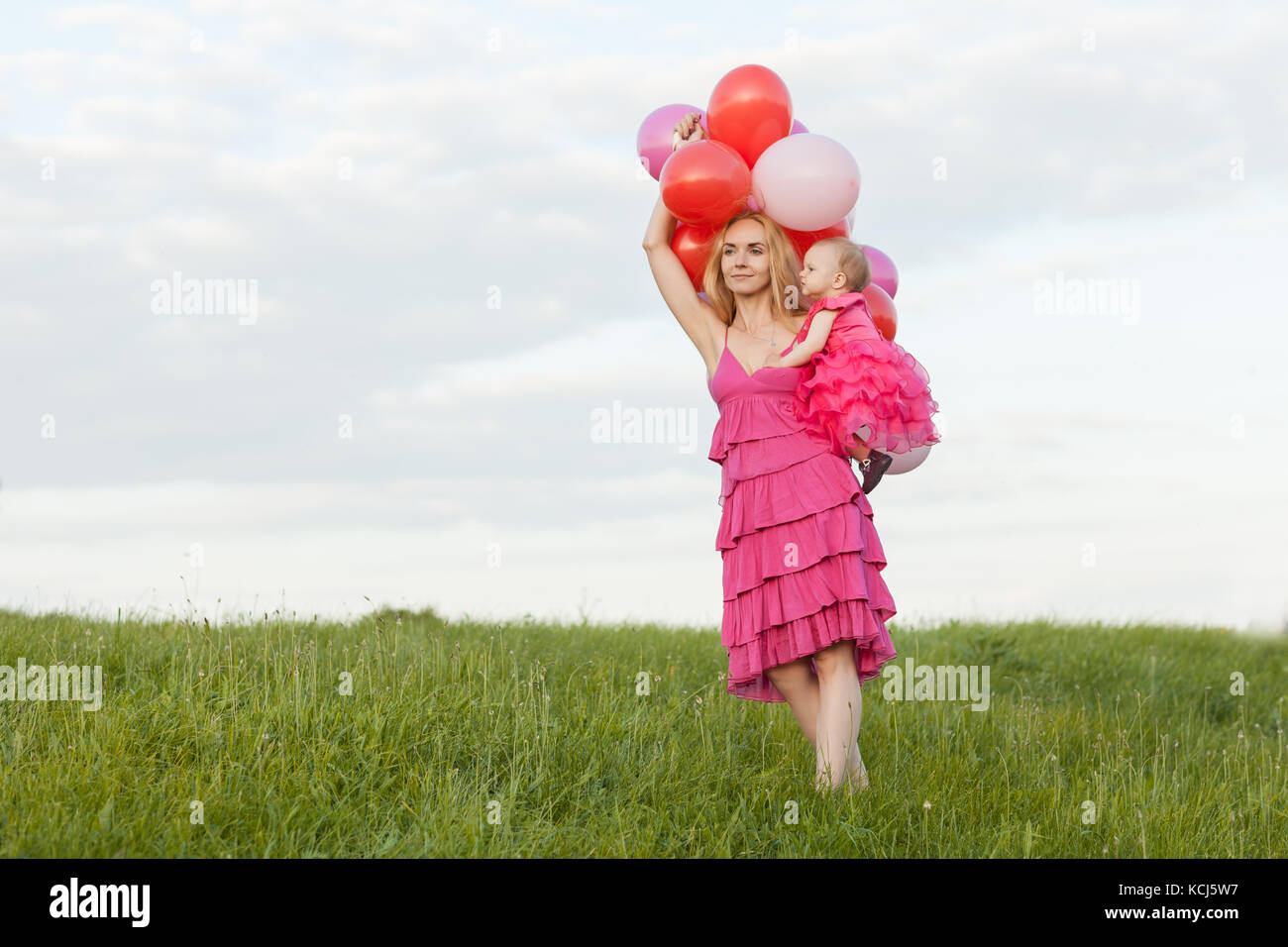 Maman est titulaire d'une fille et de ballons dans ses mains. maman est à l'avant Banque D'Images