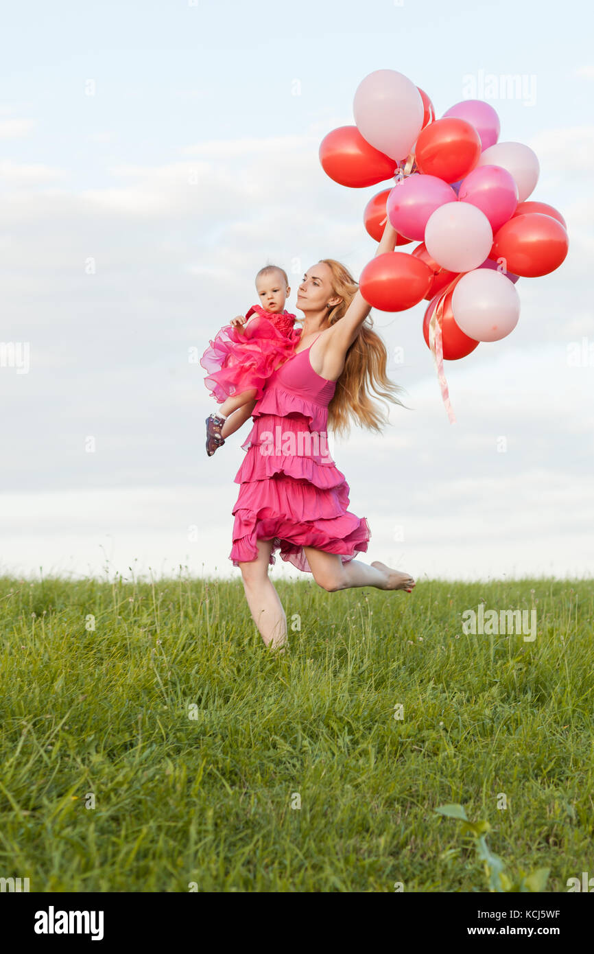 Maman est titulaire d'une fille et de ballons dans ses mains et s'étend le long de l'herbe Banque D'Images