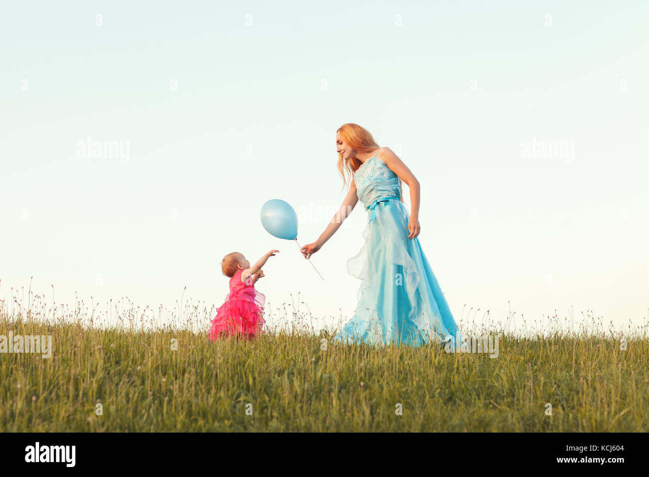 Young blonde woman giving her daughter un ballon Banque D'Images