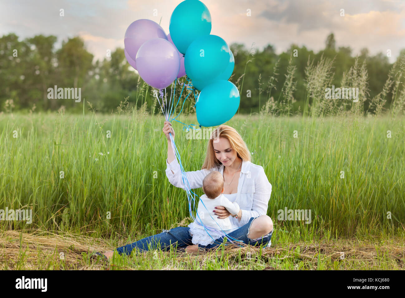 Maman est assise sur l'herbe avec un enfant. maman avec des ballons Banque D'Images
