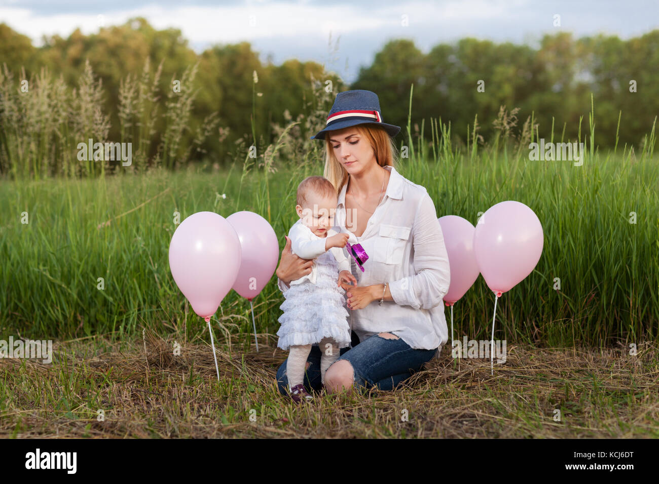 Mère et fille assis dans un pré entre les ballons roses Banque D'Images