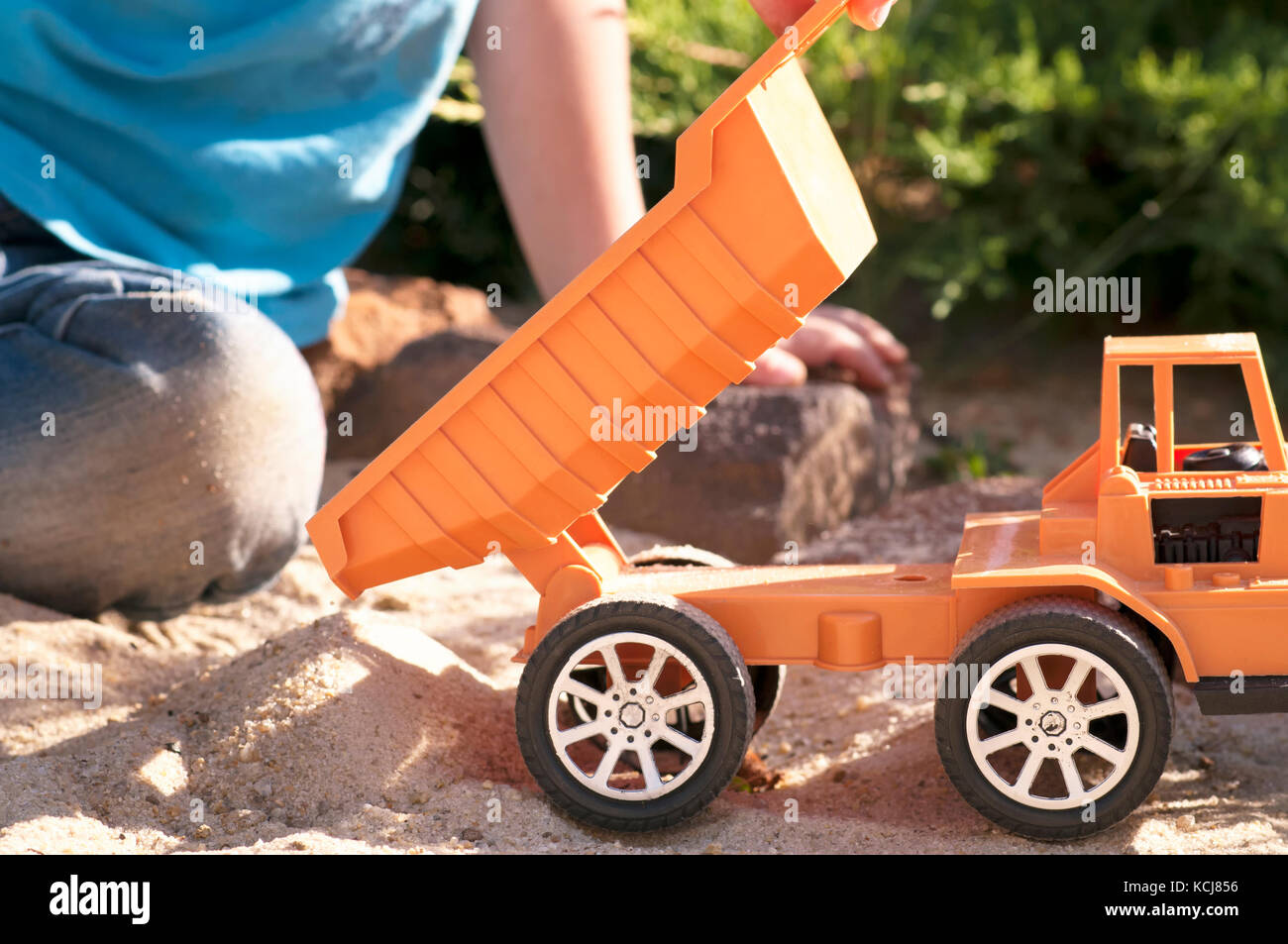 Un enfant joue dans le sable avec de grandes voitures de jouet, une pelle, un camion Banque D'Images